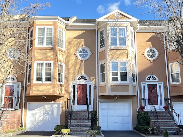 townhome / multi-family property with stucco siding, roof with shingles, and an attached garage