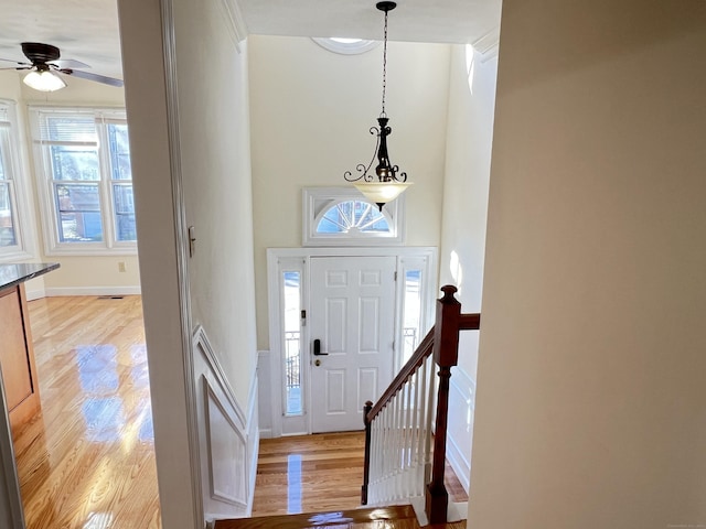 foyer with light wood-style flooring, a ceiling fan, and baseboards