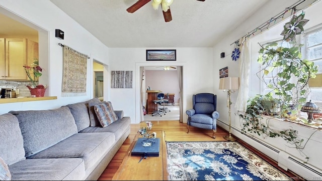 living area with a baseboard radiator, a textured ceiling, a ceiling fan, and wood finished floors