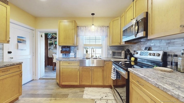 kitchen with decorative light fixtures, tasteful backsplash, appliances with stainless steel finishes, light wood-style floors, and a sink