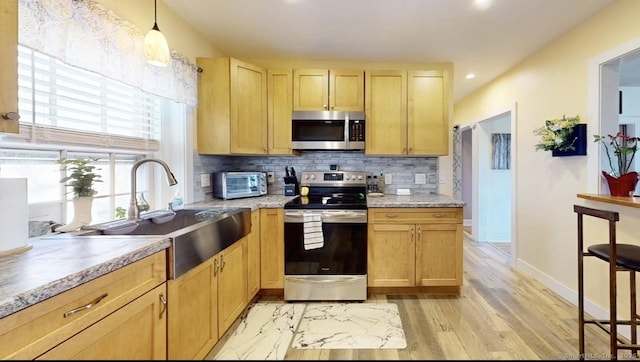 kitchen with stainless steel appliances, backsplash, a sink, and light countertops