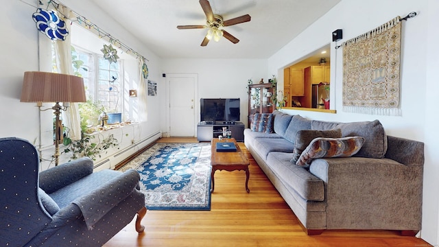 living area with baseboard heating, wood finished floors, and a ceiling fan