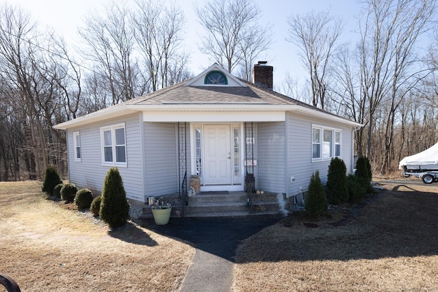 view of front of house featuring cooling unit, a chimney, and roof with shingles