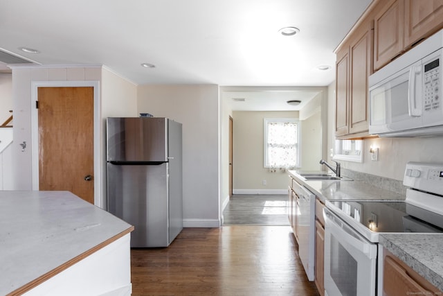 kitchen featuring dark wood-type flooring, baseboards, light countertops, white appliances, and a sink