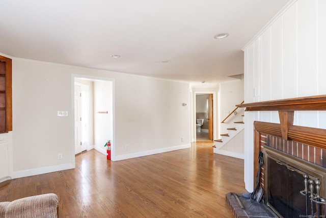 living area featuring stairway, baseboards, wood finished floors, and ornamental molding