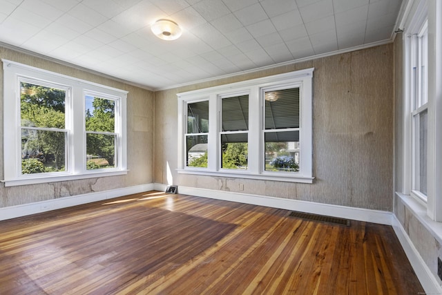 spare room with hardwood / wood-style flooring, baseboards, visible vents, and ornamental molding