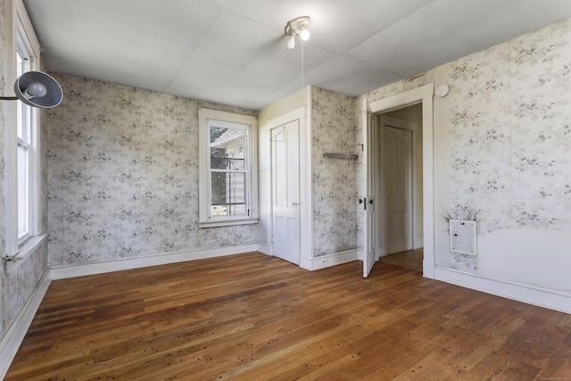 empty room with baseboards, hardwood / wood-style floors, and wallpapered walls