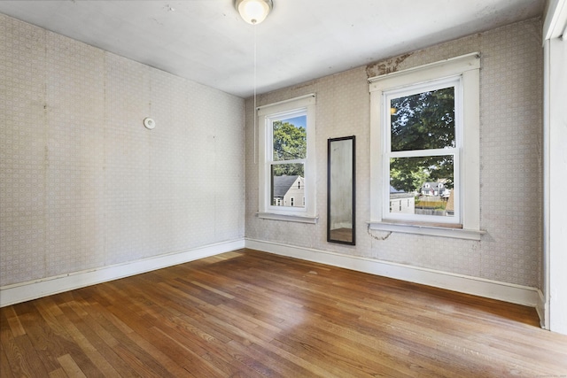 empty room featuring hardwood / wood-style flooring, baseboards, and wallpapered walls