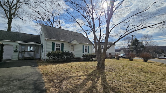 dutch colonial with aphalt driveway, a shingled roof, and a front yard