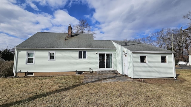 rear view of property with entry steps, a lawn, roof with shingles, and a chimney