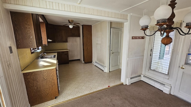 kitchen with a sink, a baseboard heating unit, crown molding, and light countertops