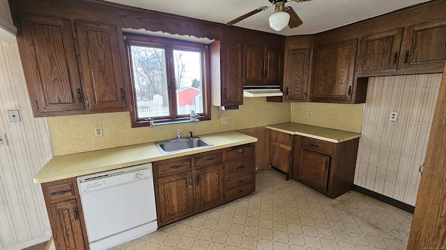 kitchen with a sink, under cabinet range hood, light countertops, light floors, and dishwasher