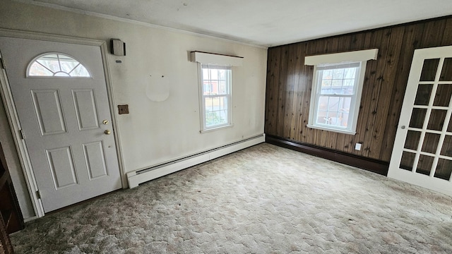 carpeted foyer with a baseboard radiator, wood walls, and crown molding