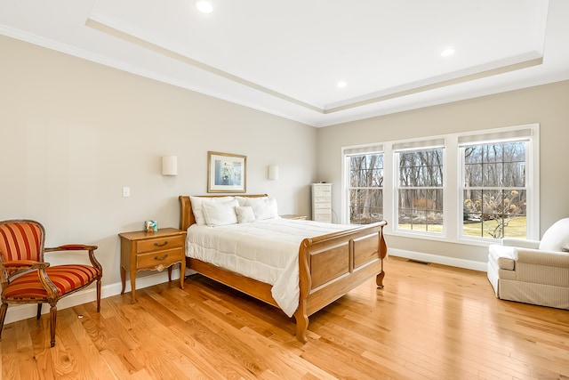 bedroom featuring a tray ceiling and light wood-style flooring