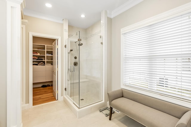 full bathroom featuring ornamental molding, a walk in closet, tile patterned flooring, and a shower stall