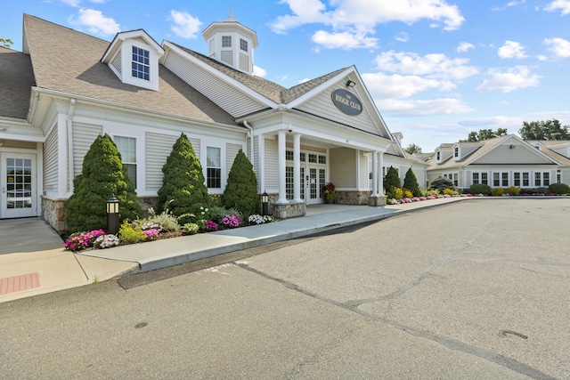 view of front of home with stone siding, french doors, and a shingled roof