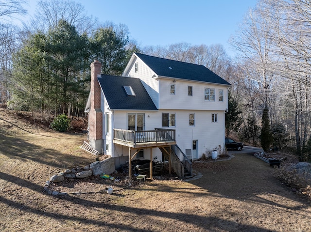 rear view of property featuring a wooden deck, a chimney, stairs, and a shingled roof