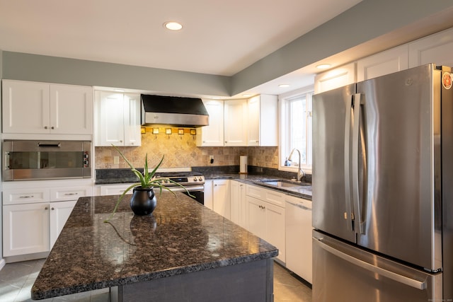 kitchen featuring a sink, wall chimney range hood, tasteful backsplash, and stainless steel appliances