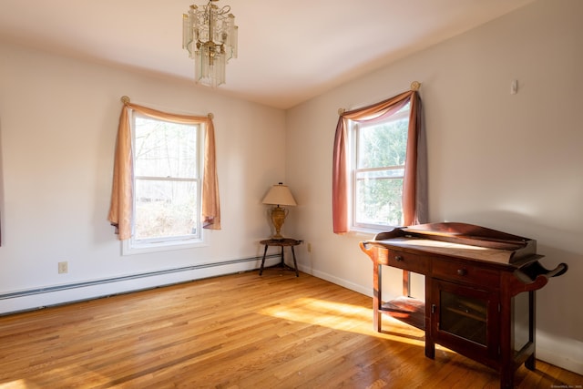 interior space with a chandelier, baseboard heating, baseboards, and wood finished floors