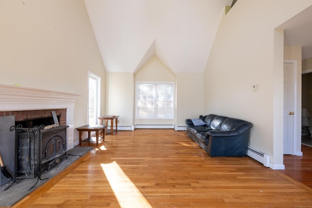 sitting room with wood finished floors, baseboards, lofted ceiling, a wood stove, and baseboard heating