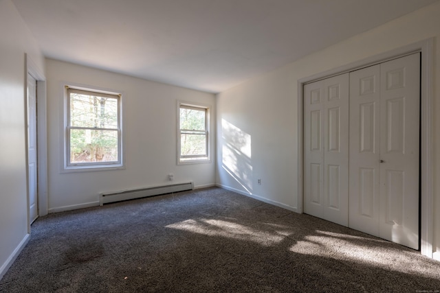 unfurnished bedroom with a closet, baseboards, dark carpet, and a baseboard radiator