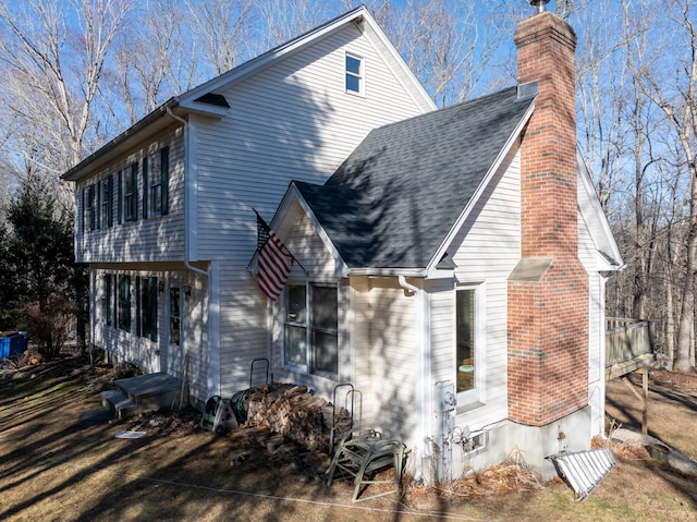 exterior space featuring roof with shingles and a chimney