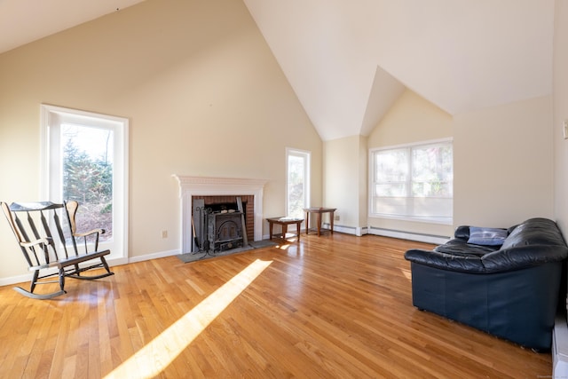 living room featuring baseboards, high vaulted ceiling, and light wood-style flooring