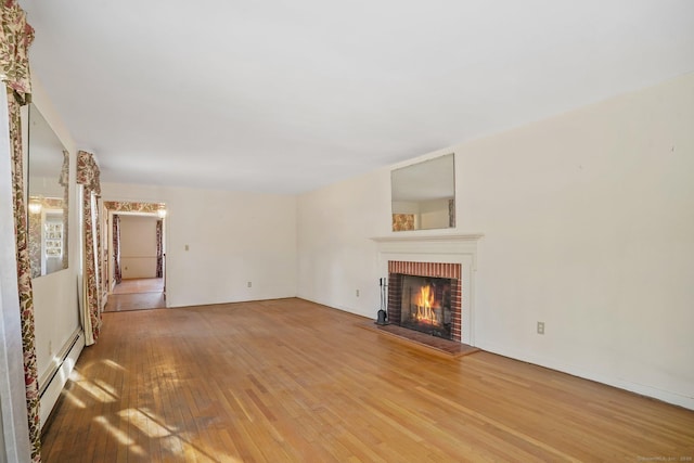 unfurnished living room with a baseboard radiator, a brick fireplace, and hardwood / wood-style flooring