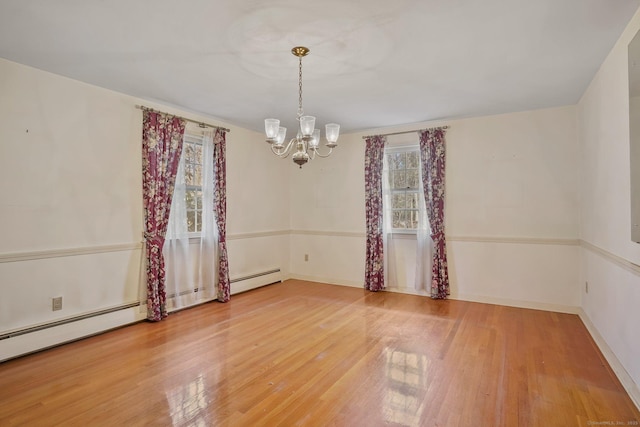 spare room with a chandelier, baseboards, and hardwood / wood-style flooring