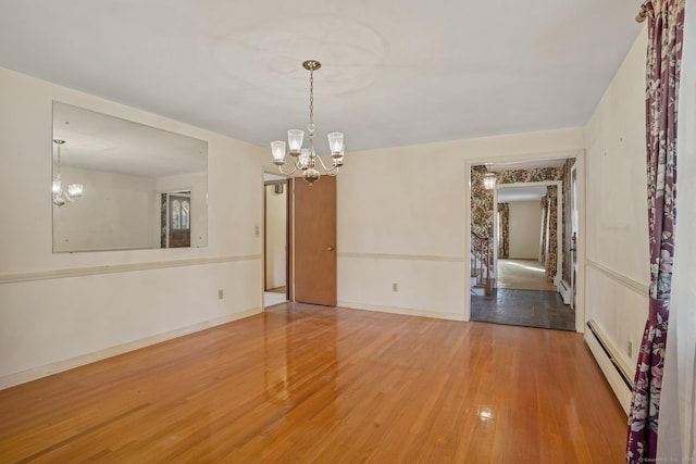 unfurnished room featuring hardwood / wood-style flooring, a notable chandelier, baseboards, and baseboard heating