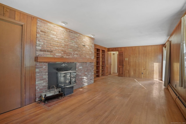 unfurnished living room featuring built in features, wood finished floors, wood walls, and baseboard heating