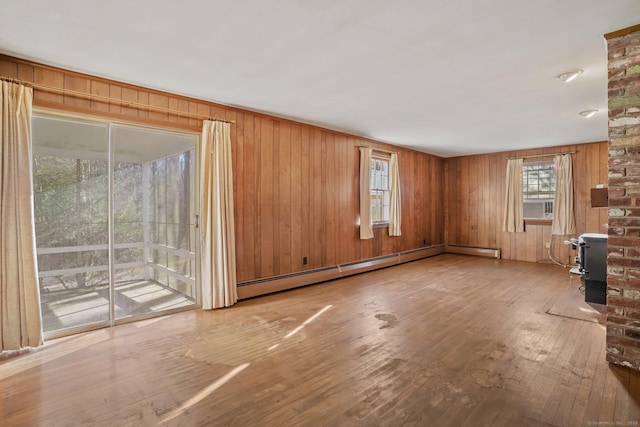 unfurnished living room featuring a baseboard radiator, wood-type flooring, and wood walls