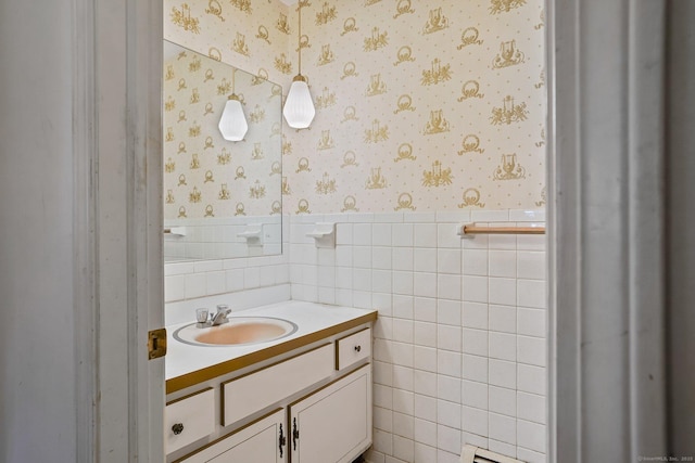 bathroom with tile walls, wainscoting, wallpapered walls, and vanity