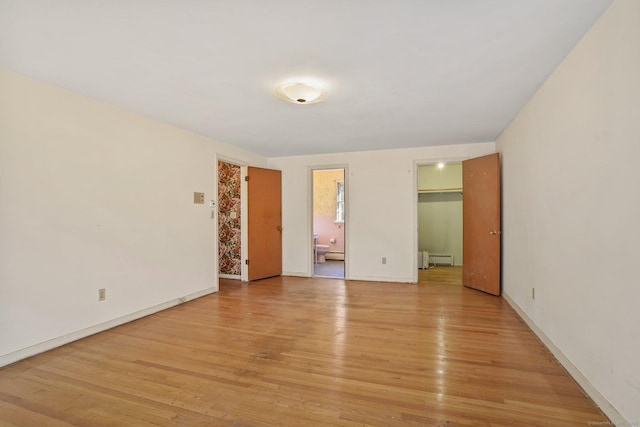 empty room with light wood-style flooring, baseboards, and baseboard heating