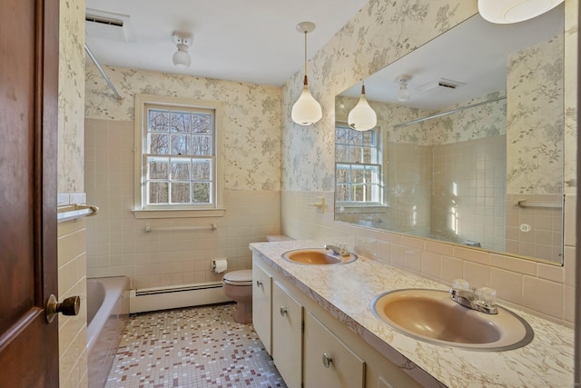 bathroom featuring wallpapered walls, a wainscoted wall, baseboard heating, and a sink