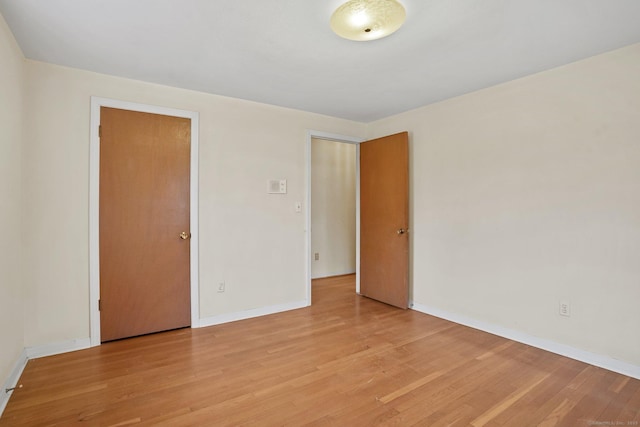 spare room with baseboards and light wood finished floors