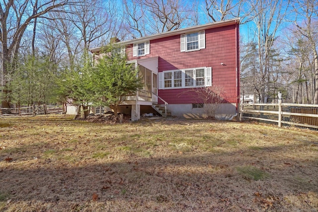 rear view of property featuring a yard, fence, a chimney, and a sunroom