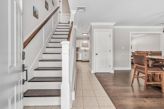 staircase featuring ornamental molding, visible vents, baseboards, and tile patterned floors