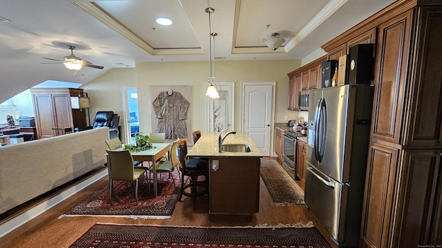 kitchen featuring a kitchen bar, a sink, appliances with stainless steel finishes, light stone countertops, and dark wood-style flooring