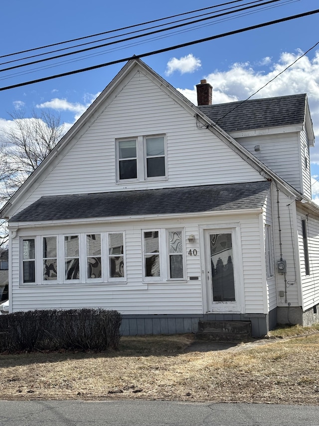 view of front of home with entry steps, a chimney, and roof with shingles