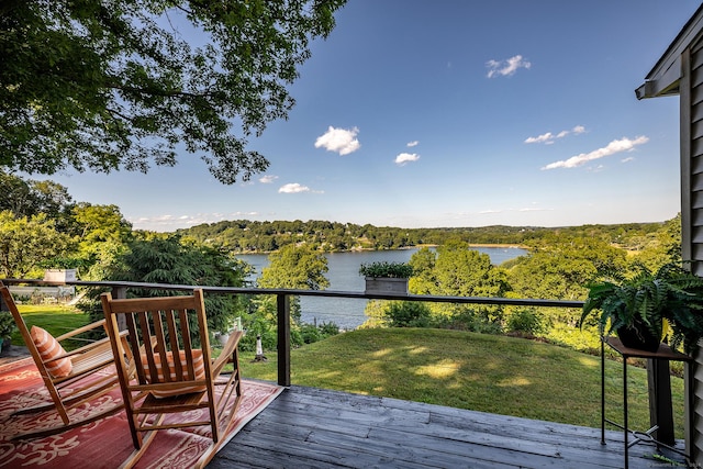 wooden terrace with a water view, a wooded view, and a yard