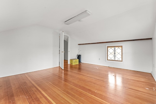 bonus room with hardwood / wood-style floors, vaulted ceiling, and baseboards