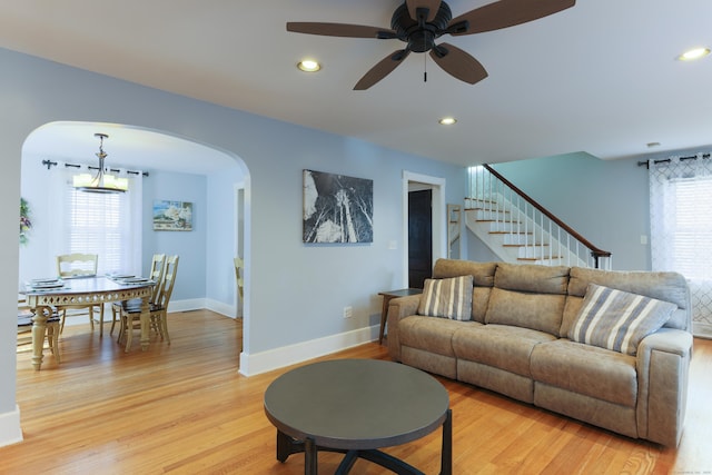 living area featuring a wealth of natural light, arched walkways, and light wood finished floors