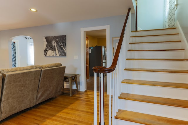 stairs featuring recessed lighting, wood finished floors, and arched walkways