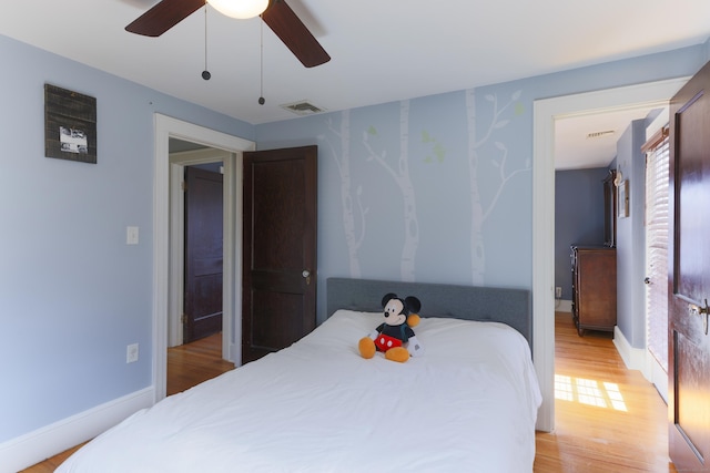 bedroom with a ceiling fan, light wood-style floors, visible vents, and baseboards