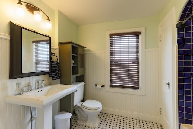 bathroom with toilet, a healthy amount of sunlight, and a wainscoted wall