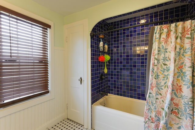 full bath featuring a wainscoted wall and shower / tub combo