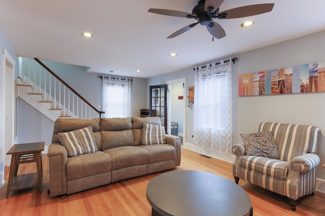 living area with recessed lighting, light wood-type flooring, visible vents, and stairs