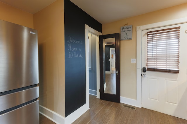 foyer entrance with wood finished floors, visible vents, and baseboards