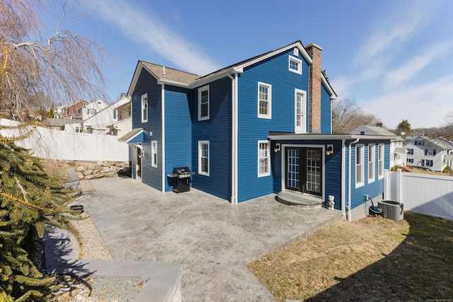 back of property with a patio area, a fenced backyard, french doors, and a chimney